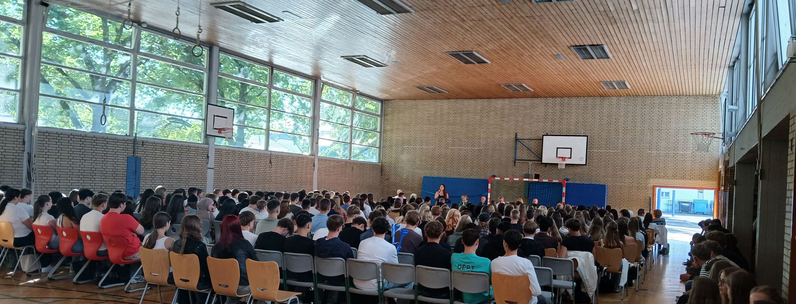Dieses Bild zeigt die neuen Schülerinnen und Schüler des Burggymnasiums Friedberg bei ihrer Einschulungsfeier in der Sporthalle.