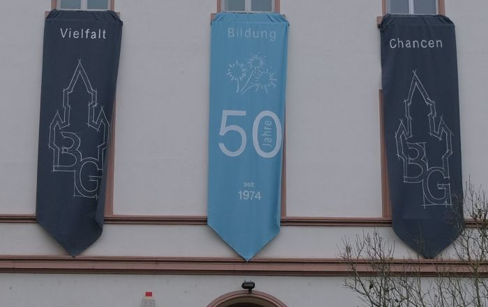 Hier sieht man die festlichen Banner "Vielfalt, Bildung, Chancen" an der Fassade des Burggymnasiums