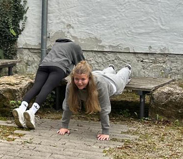 2025-10-02_WEB_Ges&Wohlb5_Ausschnitt f HP Zwei Schülerinnen beim Fitnesstraining im Grünen Klassenzimmer.
