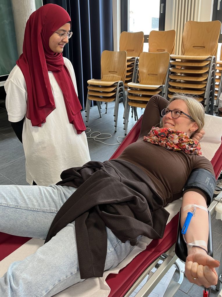 Auf diesem Foto sieht man eine blutspendende Lehrkraft in guten Händen des Schulsanitätsdienstes.