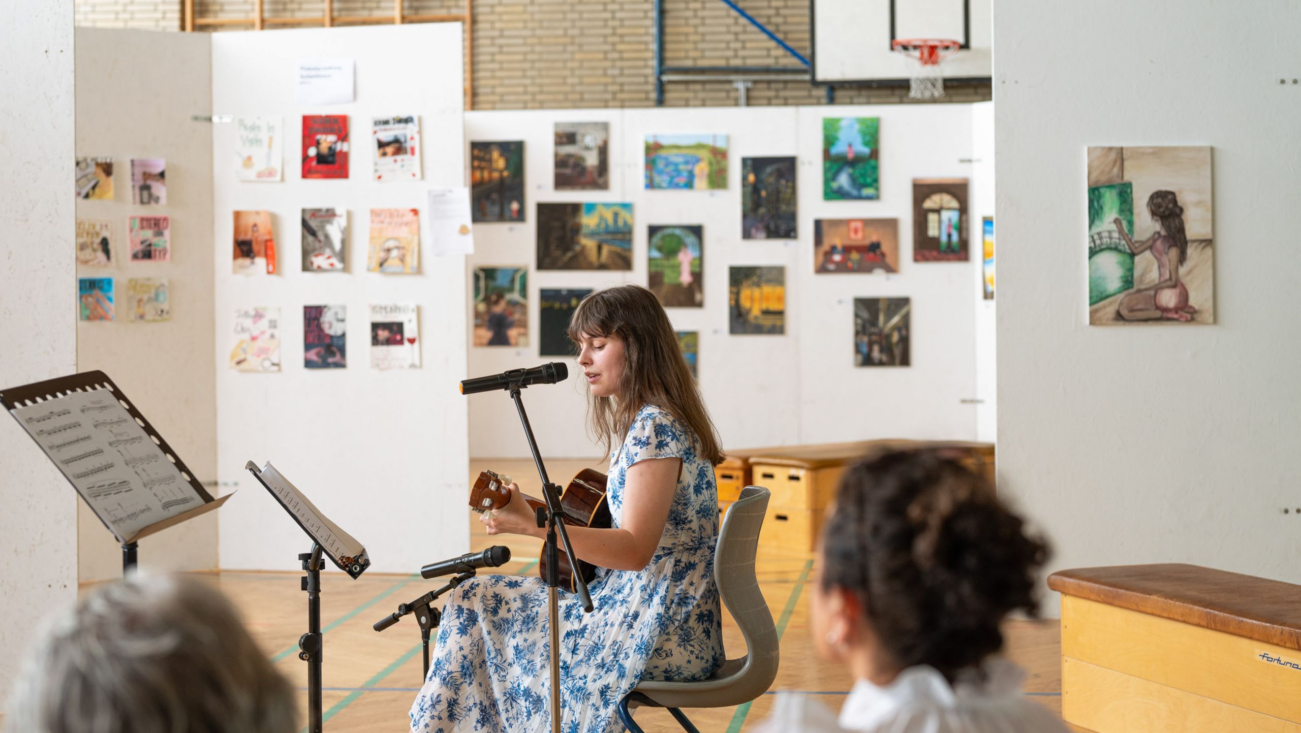 Auf diesem Foto sieht man Gitarrenspiel inmitten von Kunstwerken.
