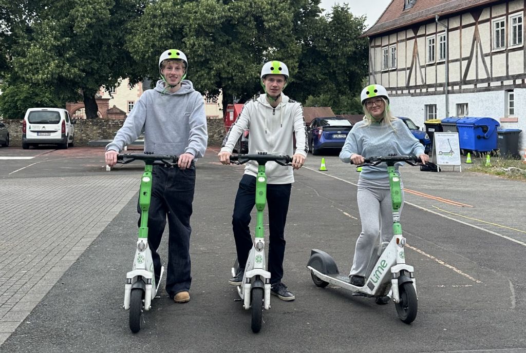 Schülerinnen und Schüler des Burggymnasiums Friedberg mit Helmen auf E-Scootern beim Sicherheitstraining