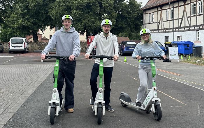 Schülerinnen und Schüler des Burggymnasiums Friedberg mit Helmen auf E-Scootern beim Sicherheitstraining