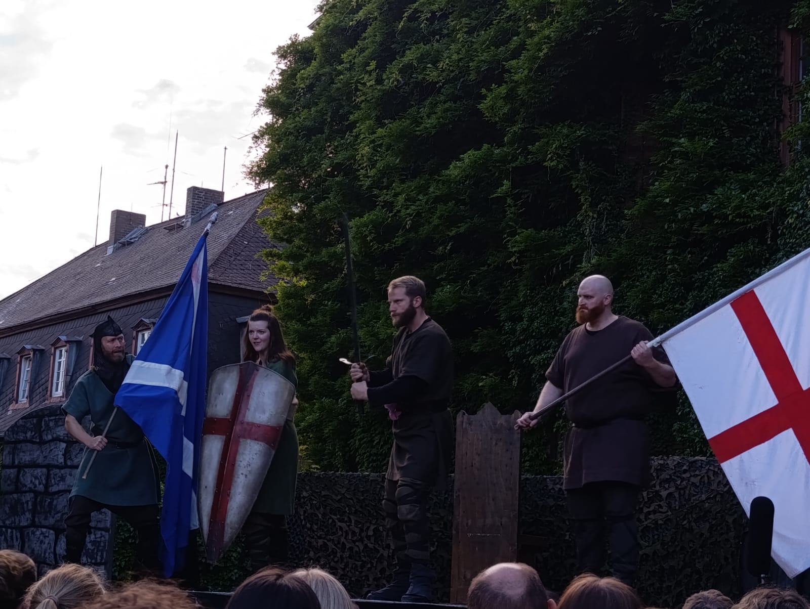 Schauspielszene der englischsprachigen Macbeth-Aufführung auf Schloss Laubach mit Fahnen und Schilden