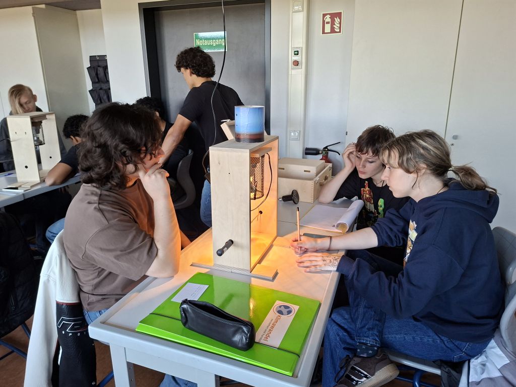 Schülerinnen und Schüler experimentieren mit einem Klimakoffer zur Wärmestrahlung.