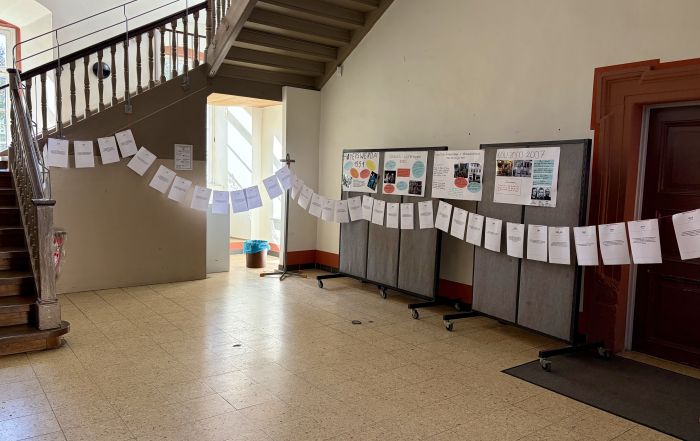 Eine Zeitleiste aus aufgehängten Blättern und Rechercheplakate zu rechter Gewalt im Treppenhaus.
